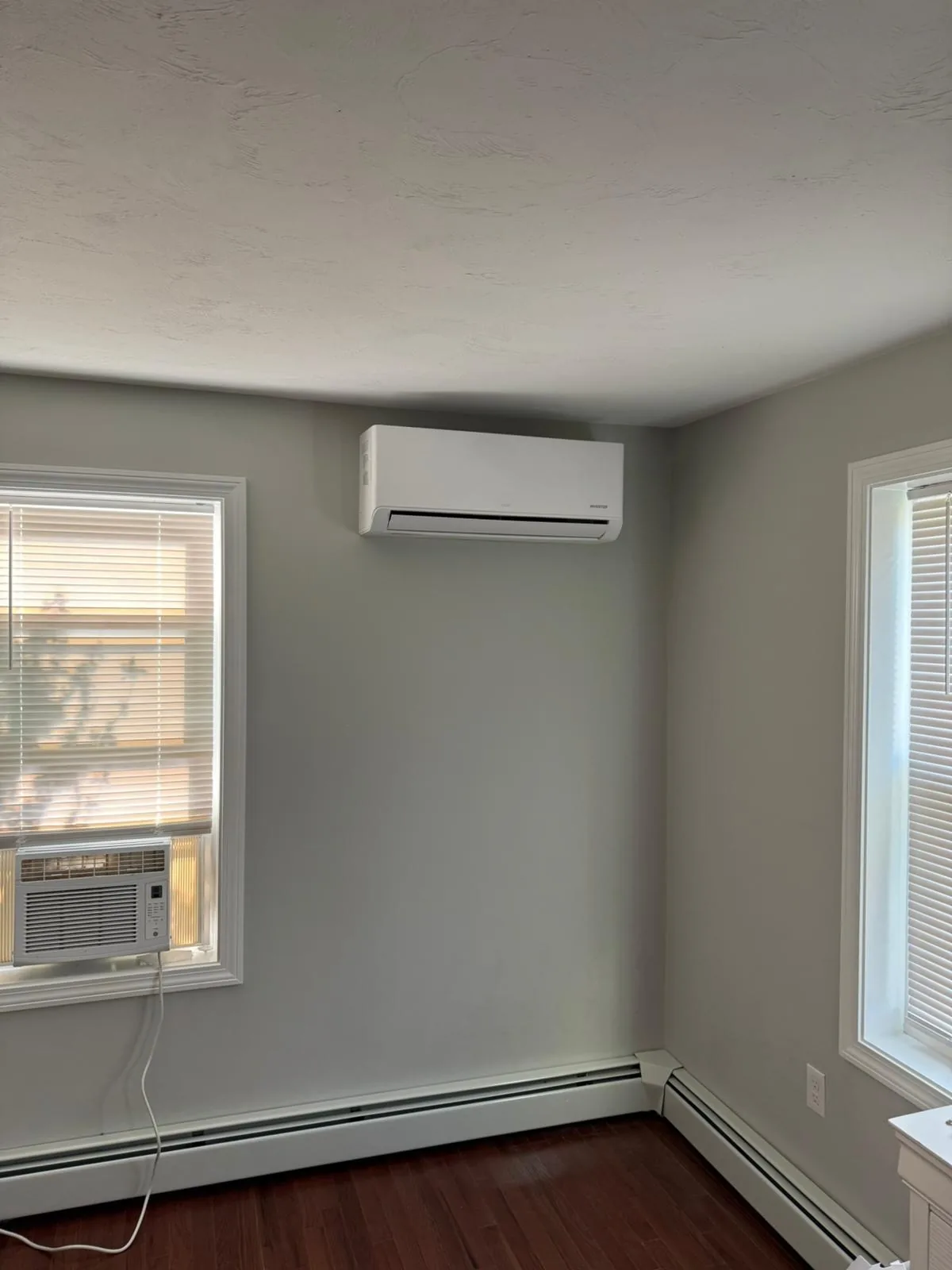 Indoor mini-split unit mounted in a mostly empty gray room