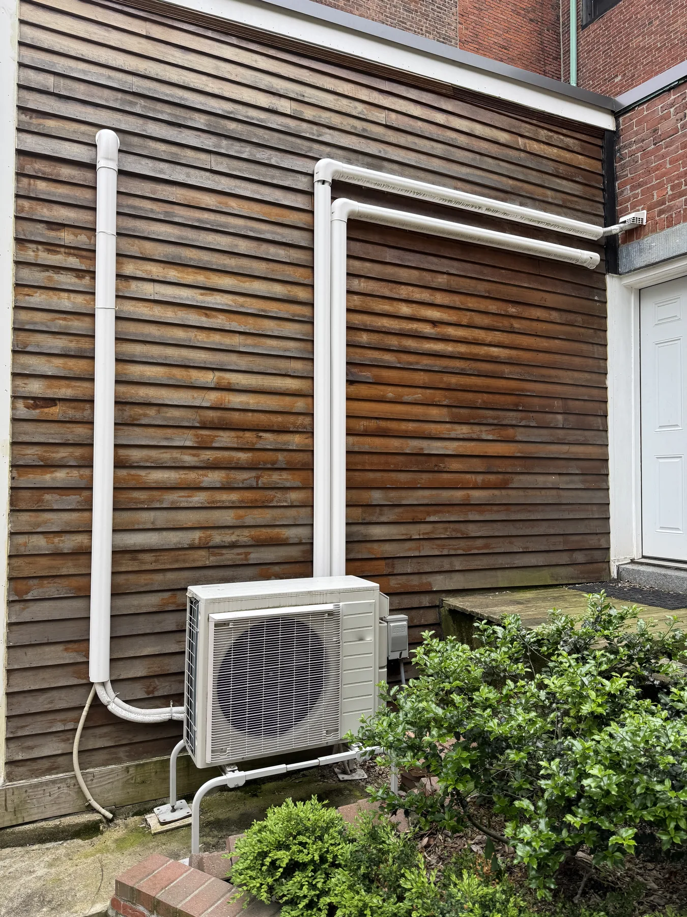 Outdoor mini-split unit and line sets installed beside a customer's home
